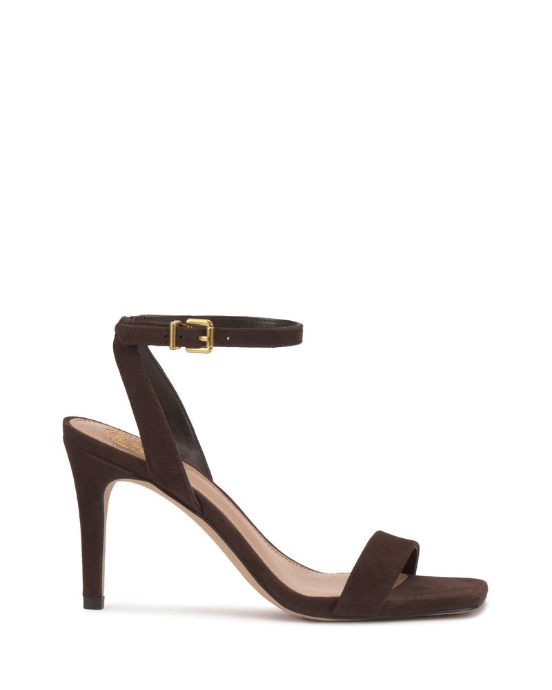 The Saprenda Sandal by Vince Camuto is a dark brown suede stiletto with an open toe, single toe strap, and ankle strap featuring a gold buckle, shown against a white background.