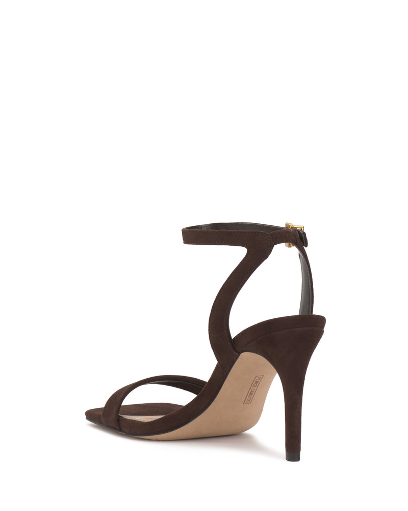 The Vince Camuto Saprenda Sandal, crafted from rich metallic leather in brown with an ankle strap and back zipper, is displayed from the rear on a white background.