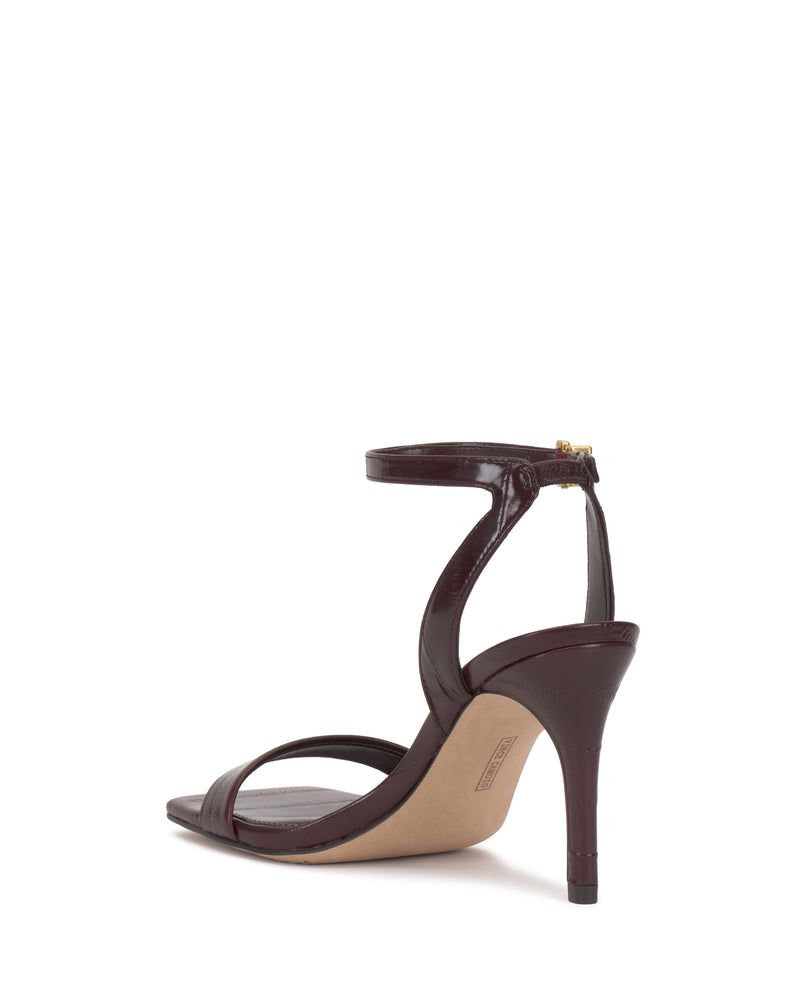The Vince Camuto Saprenda Sandal, a single maroon dress shoe with an open toe, ankle strap, and thin heel, is displayed from the back right angle against a white background.