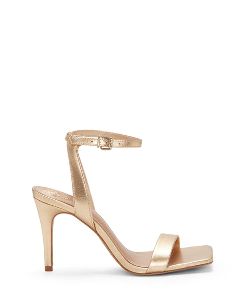 The Vince Camuto Saprenda Sandal is a gold metallic high-heeled shoe featuring an open toe, single toe strap, and ankle strap with a small buckle, displayed in profile on a white background.