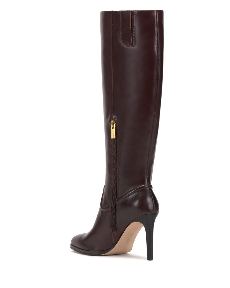The Sareya Wide Calf Knee High Boot by Vince Camuto is displayed in profile, showcasing its tall silhouette in dark brown leather with a sleek, polished finish. It features a pointed toe, a thin high heel, and a gold zipper accent.