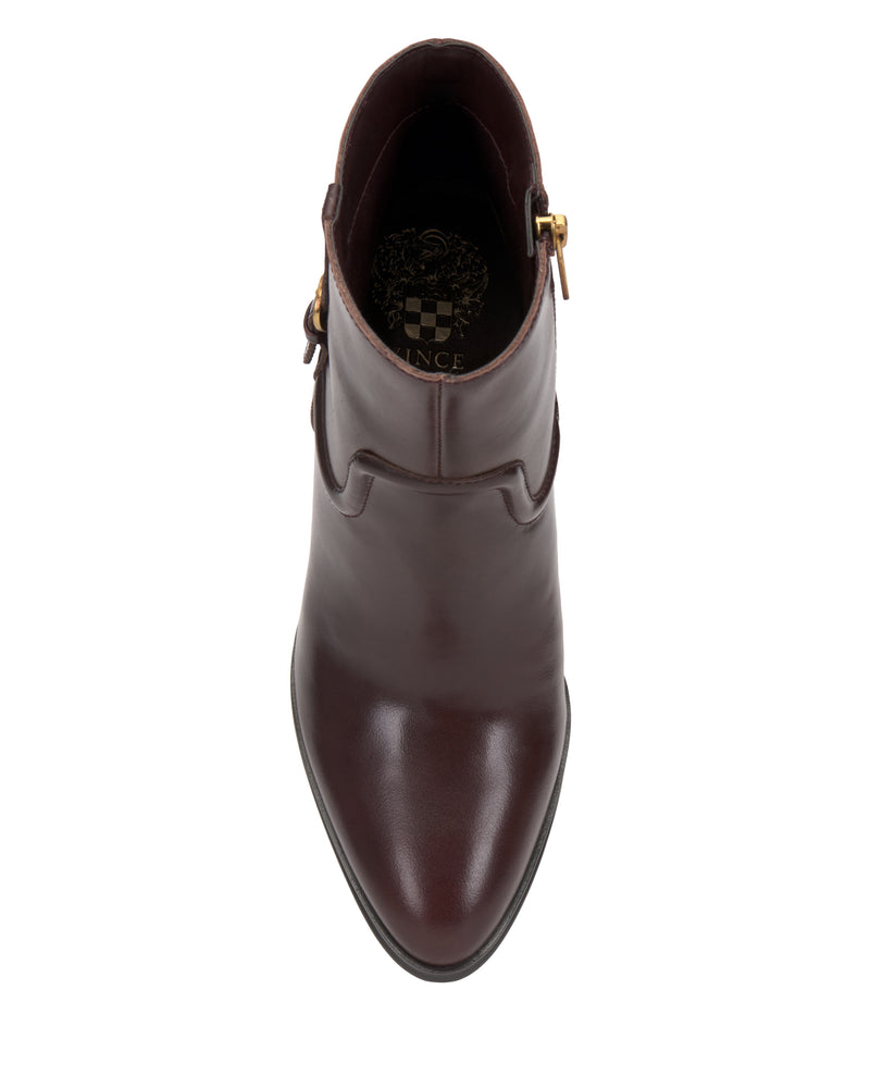 Top view of the Vince Camuto Setily Bootie—a single brown leather ankle boot featuring a pointed toe, gold buckle detail, and decorative stitching—displayed on a white background.