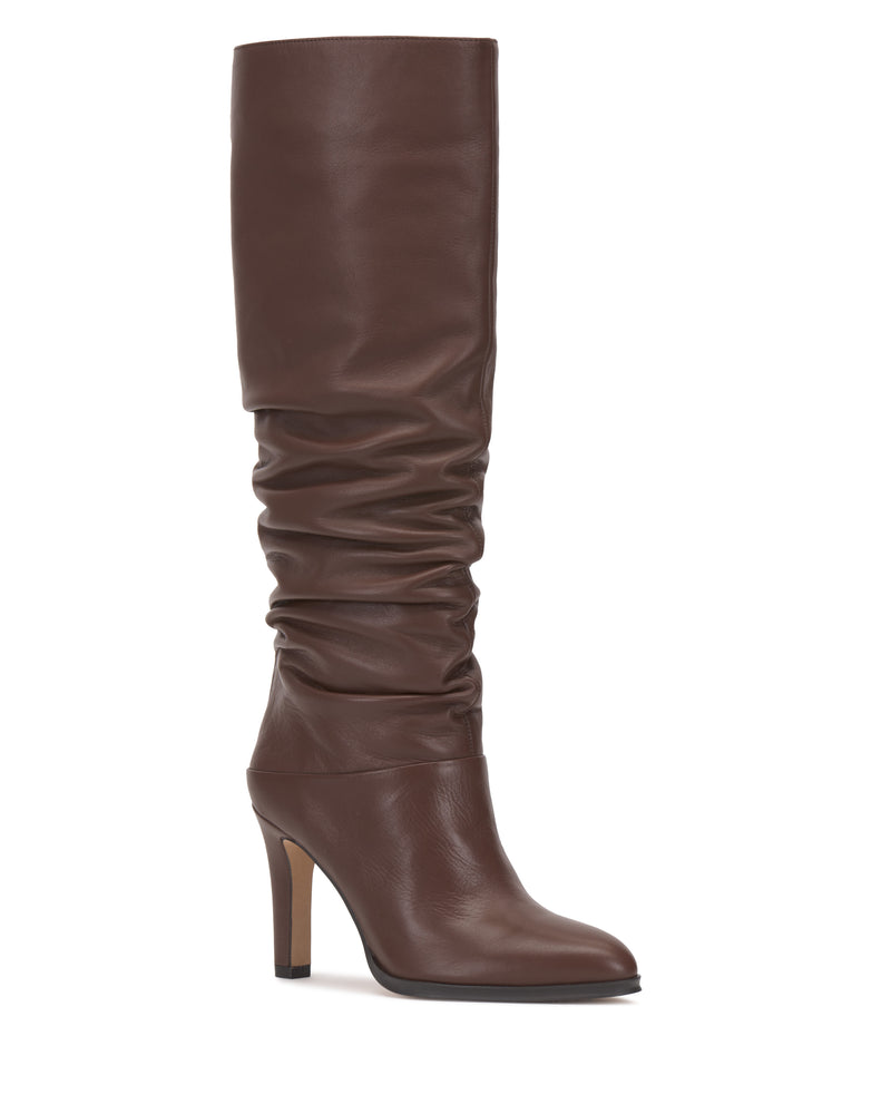 The Sorina Knee High Boot by Vince Camuto is a tall, brown leather slouchy boot featuring a pointed toe and towering heel, shown from the side against a white background.