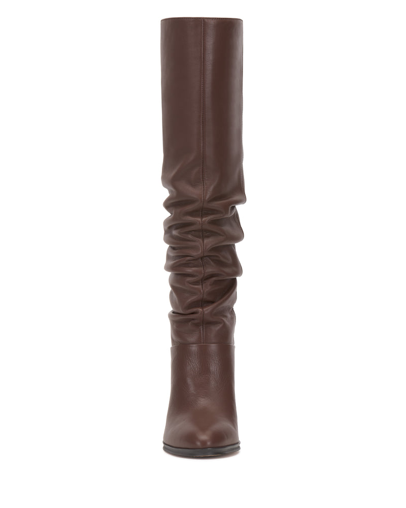 The Vince Camuto Sorina Knee High Boot is a tall, brown slouchy boot featuring a rounded toe and a relaxed midsection, shown upright from a front-facing angle against a white background.