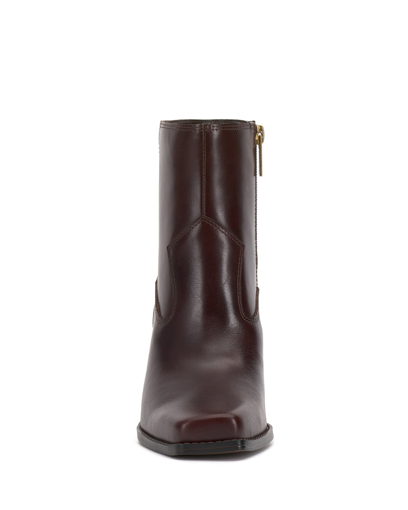 Front view of the Vince Camuto Sybren Bootie in brown leather, featuring a western-inspired design with a side zipper and a slight heel, shown against a white background.