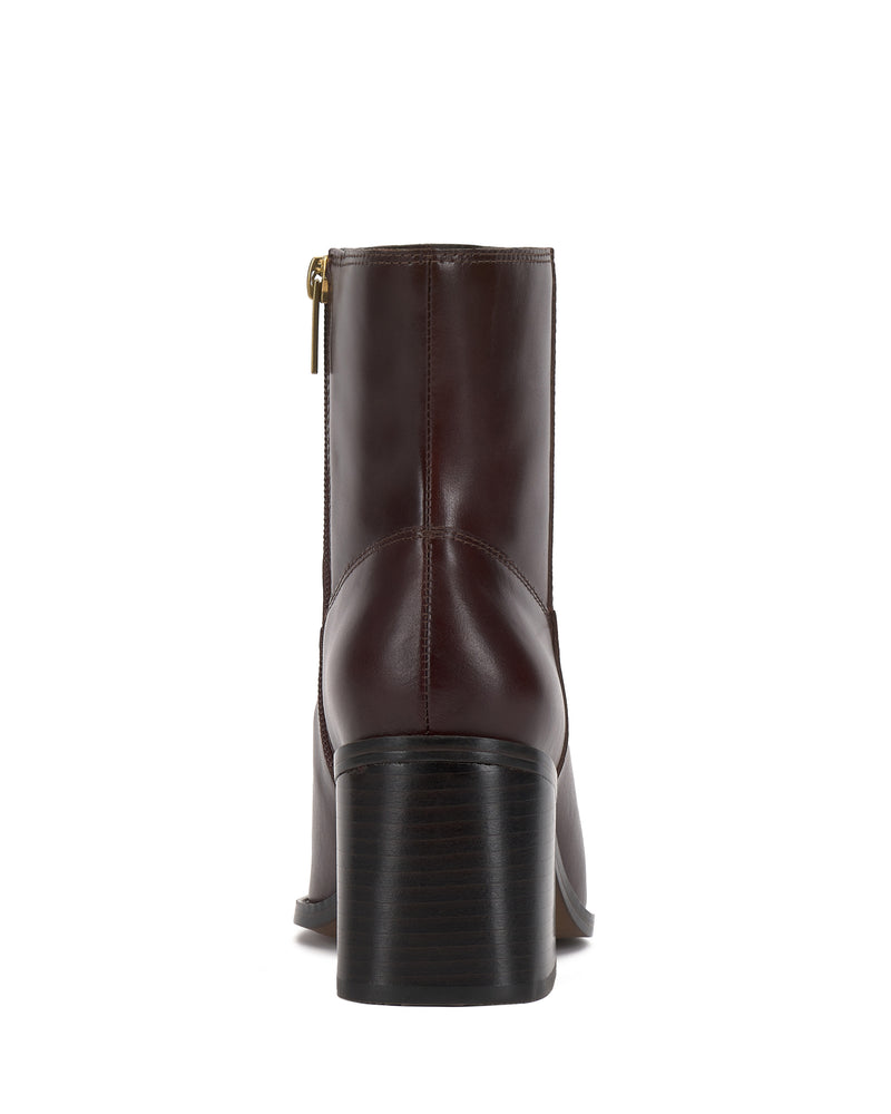 The Vince Camuto Sybren Bootie is a brown leather ankle boot with a stacked chunky block heel, shown from the back. This bootie showcases a gold side zipper and visible stitching along the seams, merging modern sophistication with timeless style.