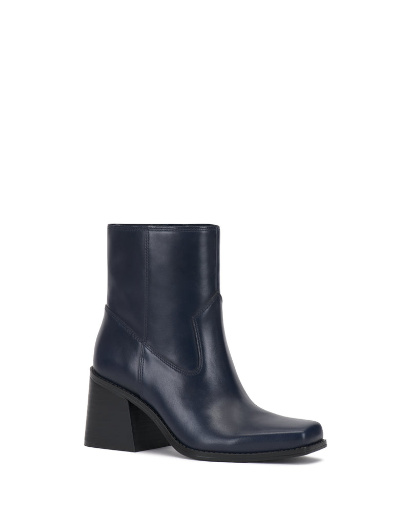The Sybren Bootie by Vince Camuto is a navy blue leather ankle boot with a structured silhouette, showcasing a medium chunky block heel and a slightly squared toe, displayed on a white background.