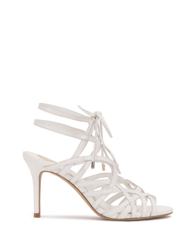 The Tilly Sandal by Vince Camuto features a white lace-up design with an open toe, thin stiletto heel, two ankle straps, and crisscross details for an elegant look.