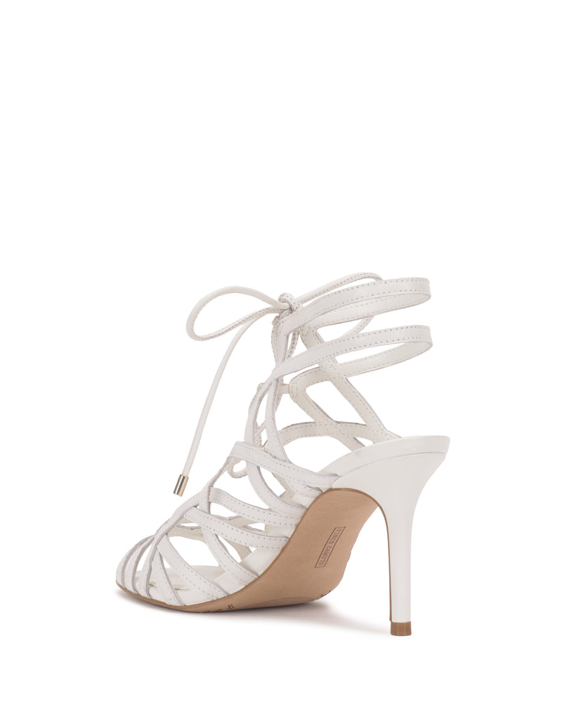 The Tilly Sandal by Vince Camuto features a white strappy design with a stiletto heel, open toe, and elegant ankle lace-up, shown angled from the back right against a plain white background.