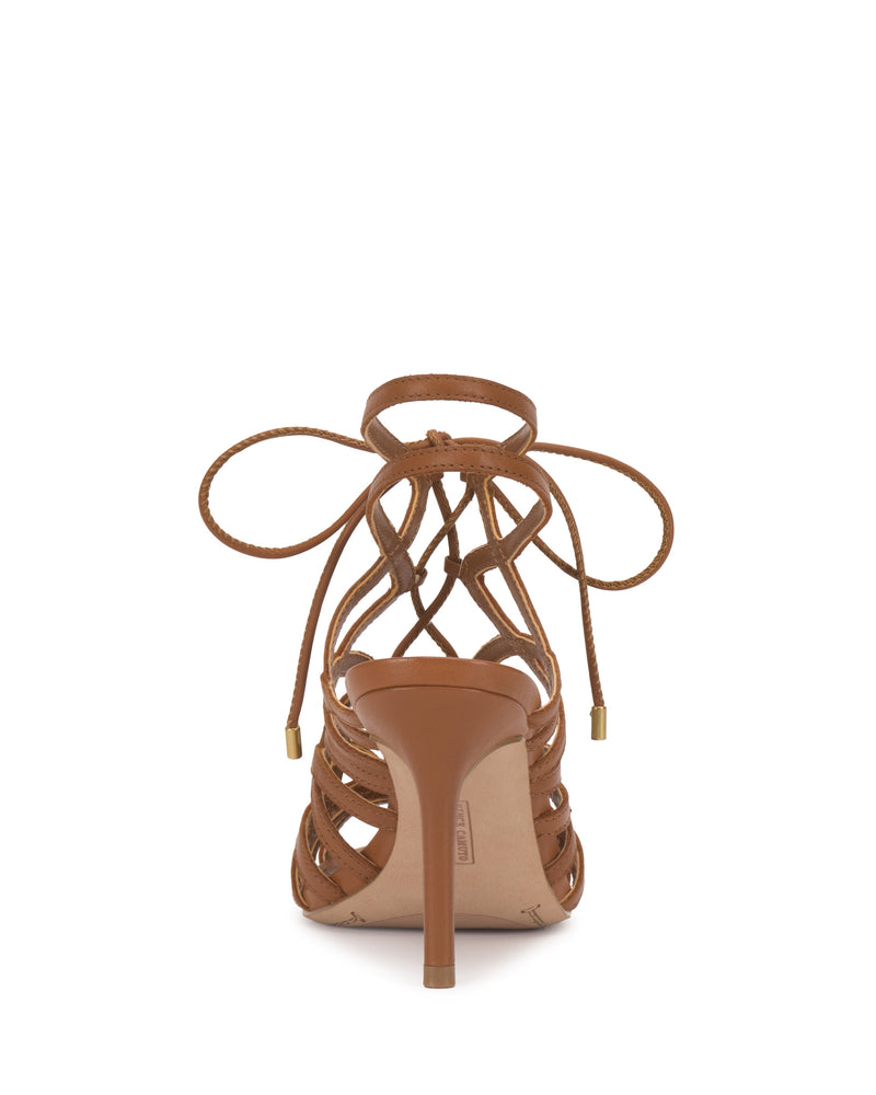 The Tilly Sandal by Vince Camuto is shown from the back, featuring a brown lace-up design with thin straps tied in a bow at the ankle and a sleek stiletto heel.