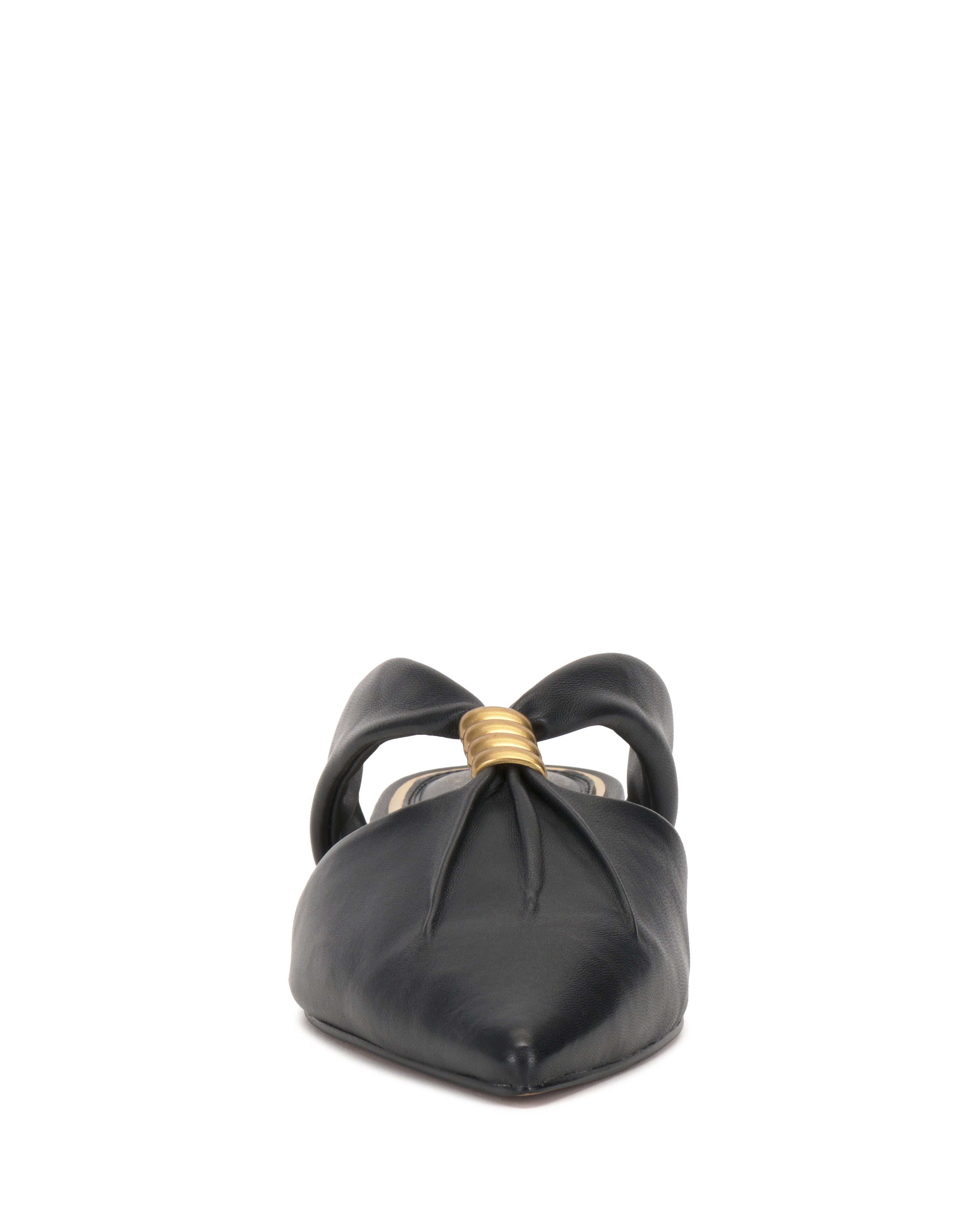 Front view of the Vince Camuto Vanika Mule, a black pointed-toe flat with a twisted knot and gold metallic accent at the knot's center.
