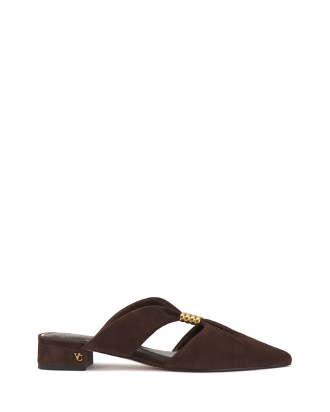 The Vanika Mule by Vince Camuto features brown suede, a pointed toe, low block heel, cutout upper, gold chain detail, and a small gold monogram on the heel.