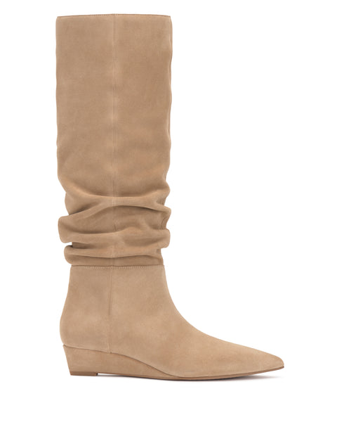 The Vanisa Knee High Boot by Vince Camuto is a tan suede knee-high boot featuring a low wedge heel, pointed toe, and slouchy shaft, shown in side profile against a white background.