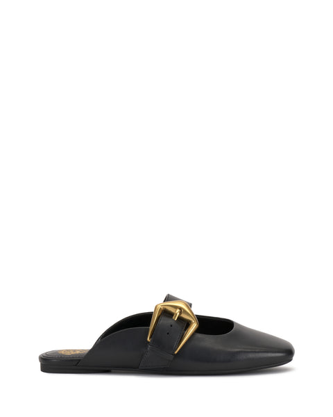 The Vellma Buckle Mule by Vince Camuto is a black leather slip-on with a pointed toe, flat sole, and features a large gold buckle detail on the upper side.