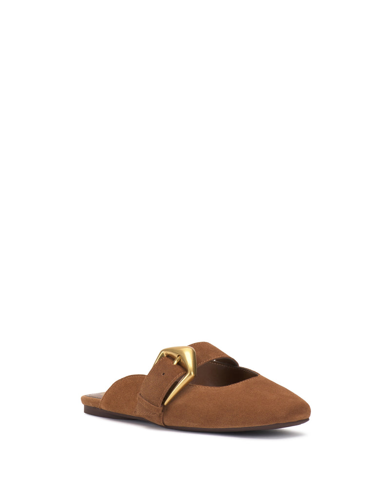 The Vince Camuto Vellma Buckle Mule is a brown suede slip-on flat featuring a pointed toe and a bold gold buckle on the upper, shown against a white background.