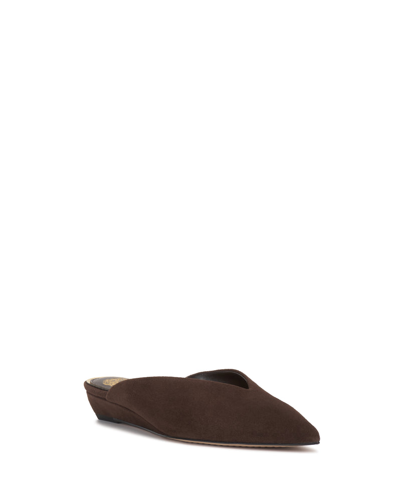 The Vinia Mule by Vince Camuto is a dark brown suede shoe featuring a low wedge heel and pointed toe, shown against a white background.
