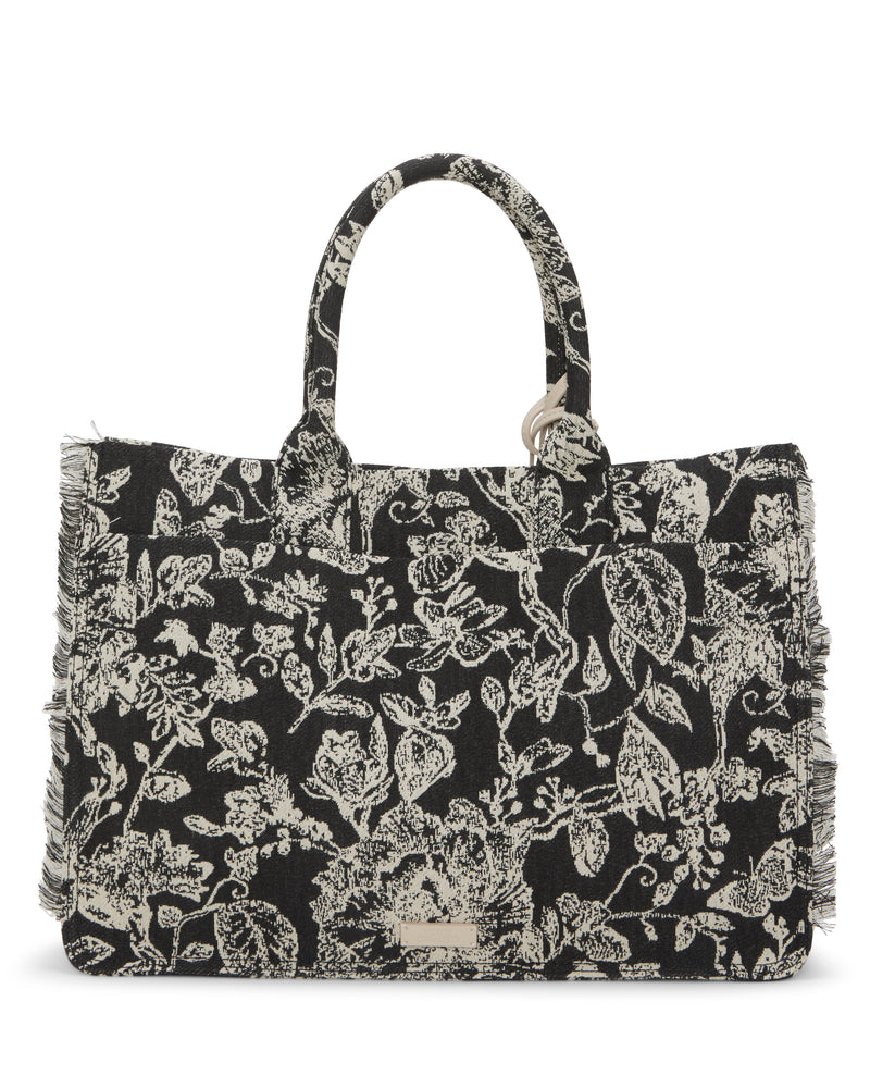 The Vince Camuto Zhury Tote Bag is black with white floral patterns, short handles, fringed edges, and a rectangular shape. A small metallic label on the front adds a chic touch.