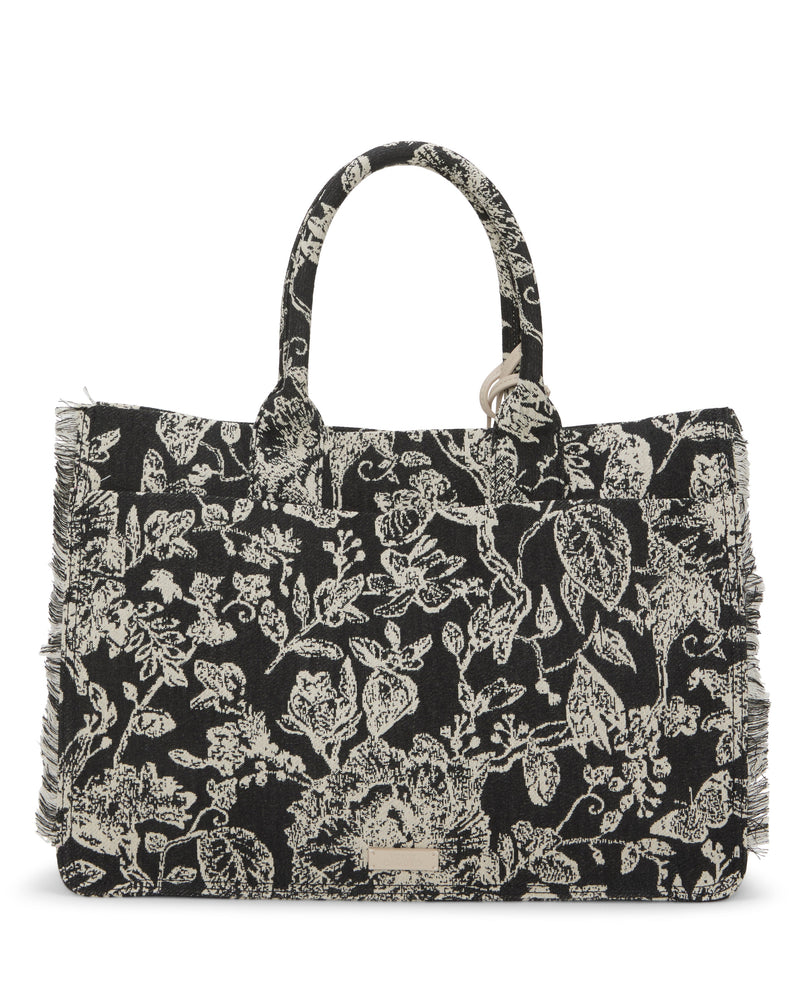 The Vince Camuto Zhury Tote Bag is a black fabric handbag with dual handles, off-white floral patterns, frayed edges, and a small metallic logo plate at the bottom center.