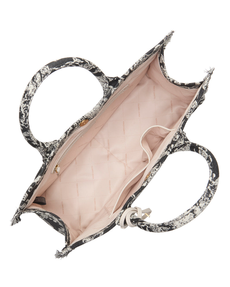 Top view of the Vince Camuto Zhury Tote Bag, showcasing its black and white patterned handles and exterior, plus a roomy light pink interior with both a zippered and an open pocket.