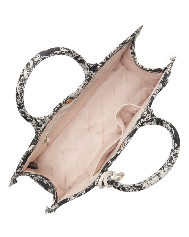 Top view of the Vince Camuto Zhury Tote Bag with dual handles, a black and white pattern, a roomy light pink interior, plus one zippered and one open pocket inside.