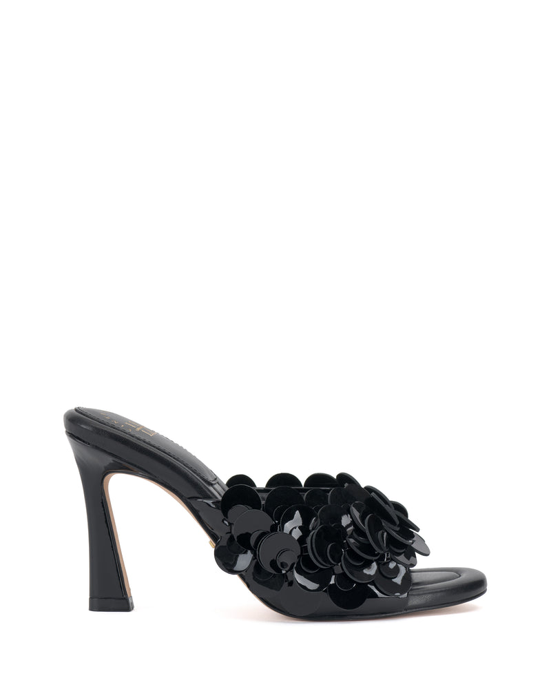 The Vince Camuto Rose Mule is a black high-heeled sandal with an open toe, glossy floral appliqués on the front strap, and a padded footbed, shown against a white background.