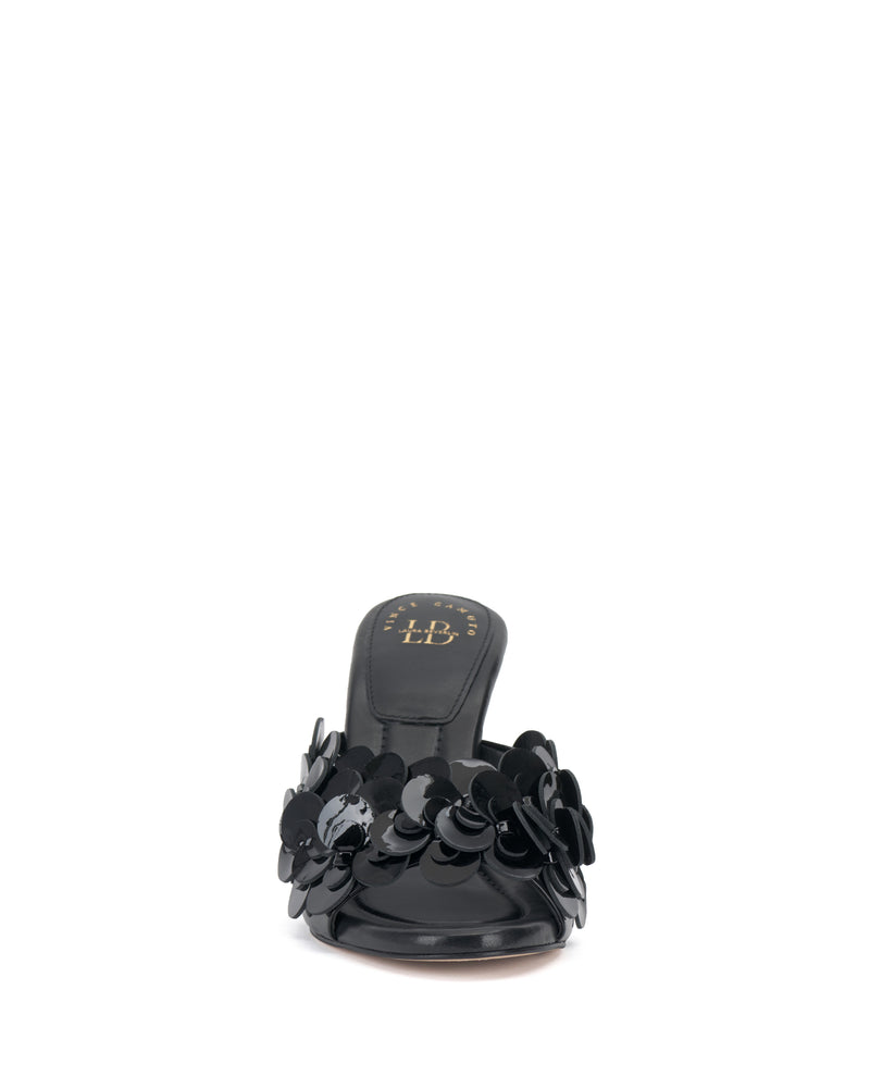 Front view of the Vince Camuto Rose Mule, a black open-toe slide featuring 3D blossom accents on the upper, low heel, cushioned footbed, and gold Vince Camuto logo on the insole.