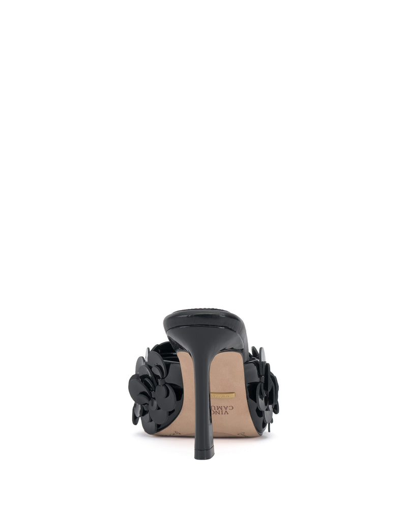 A black Vince Camuto Rose Mule viewed from the back, with decorative black flower accents on the sides, a beige sole, and a padded footbed.