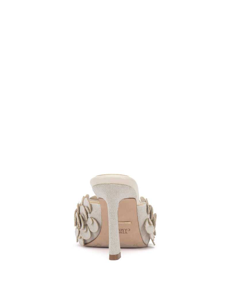 The Vince Camuto Rose Mule features a light-colored fabric upper, decorative fabric flowers on each side near the heel, a beige sole, and a comfortable padded footbed.