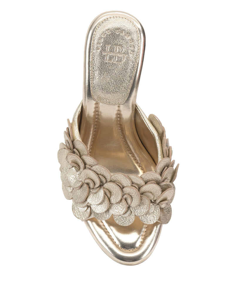 The Vince Camuto Rose Mule is a gold open-toe sandal with an overlapping circular strap design, metallic sole finish, and padded footbed for comfort, shown from a top view.