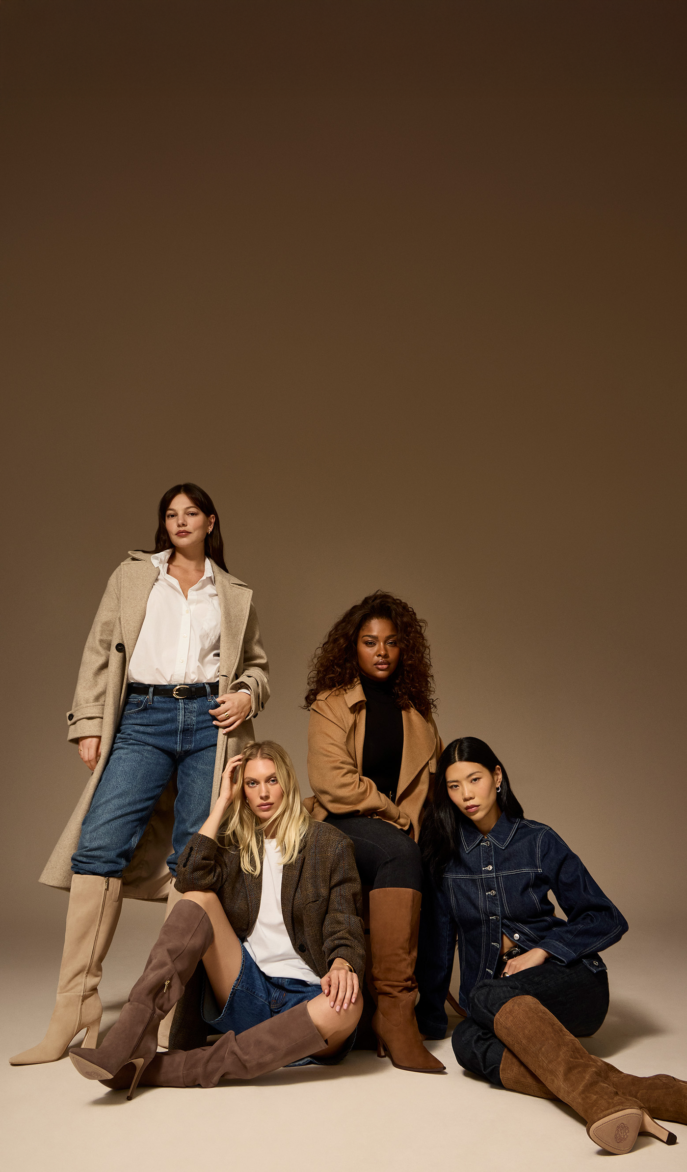 Four women posing together in a studio setting with a neutral background