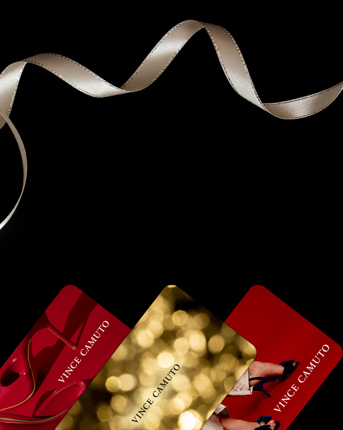 Black background with the 3 versions of the Vince Camuto E-Gift Cards on display with a gold holiday ribbon wrapping throughout