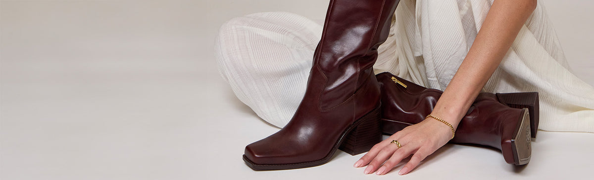 woman on gray background wearing brown knee high boots