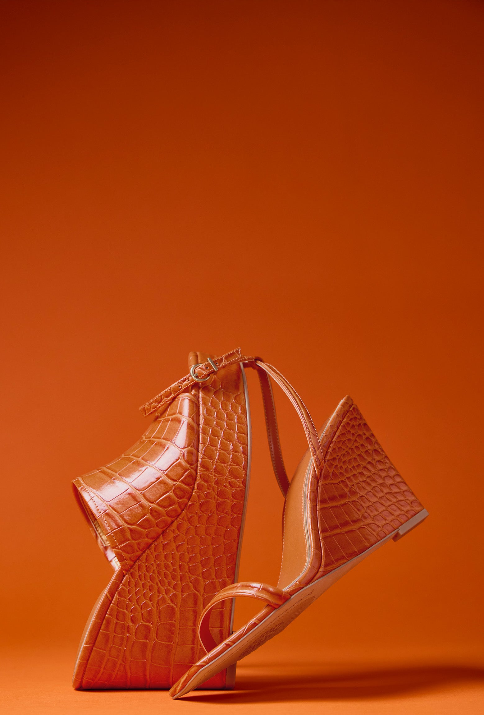 Pair of high-heeled shoes with a textured design on an orange background