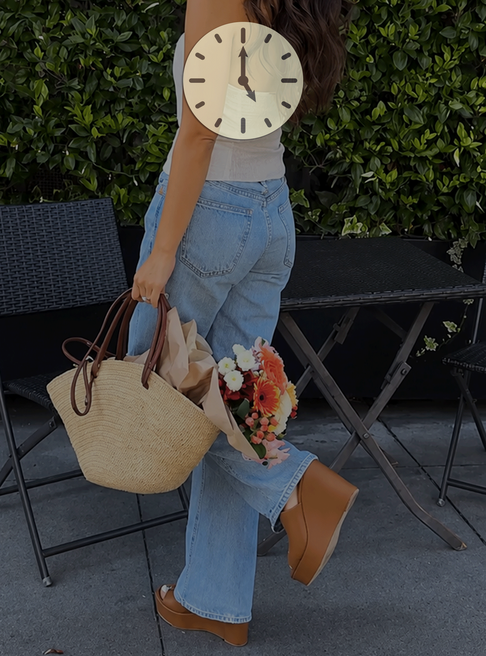 woman in wedge sandals holding a tan bag with flowers