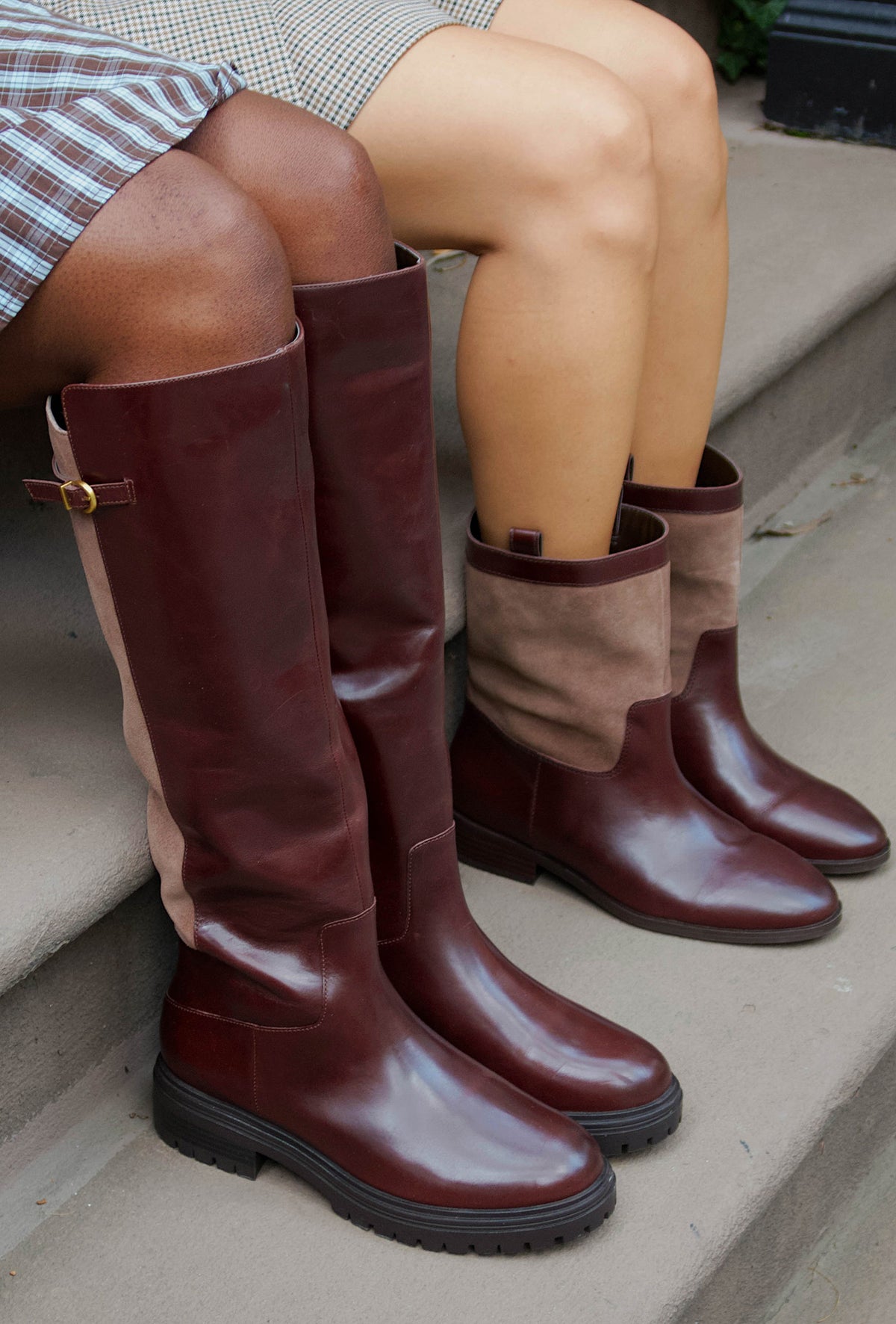 two women wearing brown boots siting on concrete steps