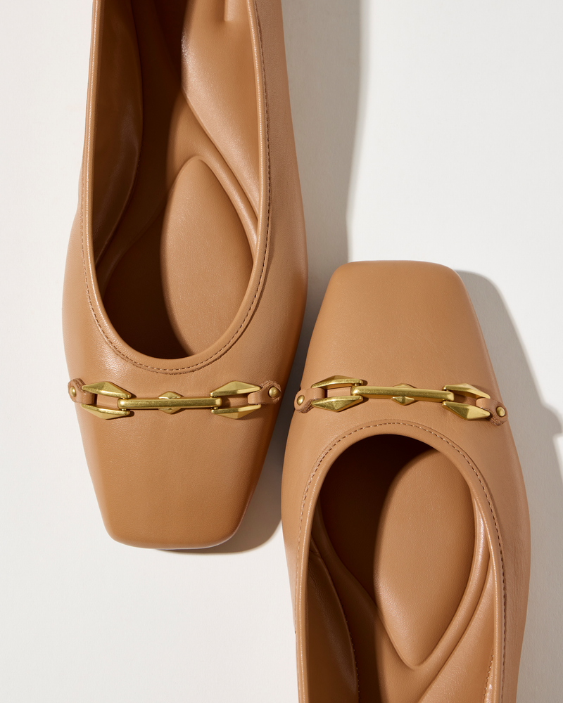 The Virna Link Ballet Flat by Vince Camuto is a tan leather square-toe ballet flat featuring gold chain accents for modern style, shown against a white background.
