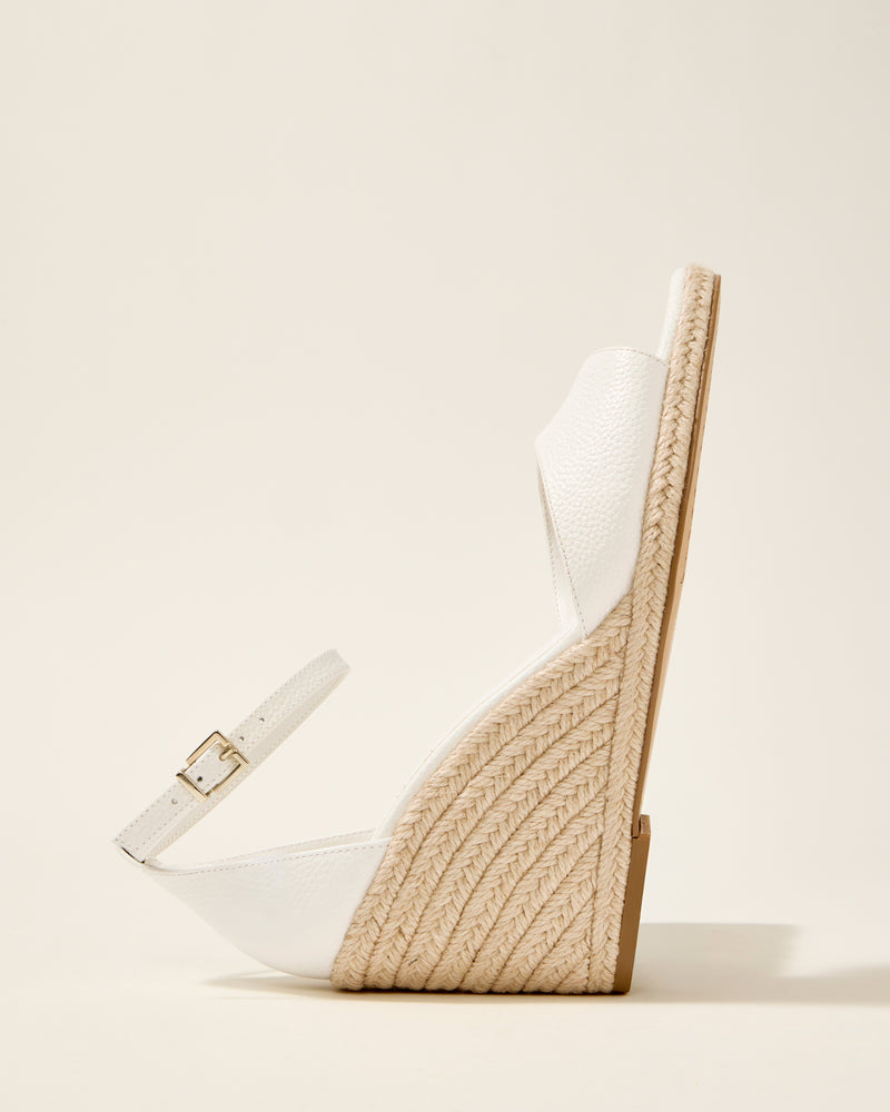 The Vince Camuto Felyn Espadrille Wedge Sandal is shown in profile against a plain light background, featuring a white design with a textured ankle strap, buckle, and a high braided jute wedge heel.