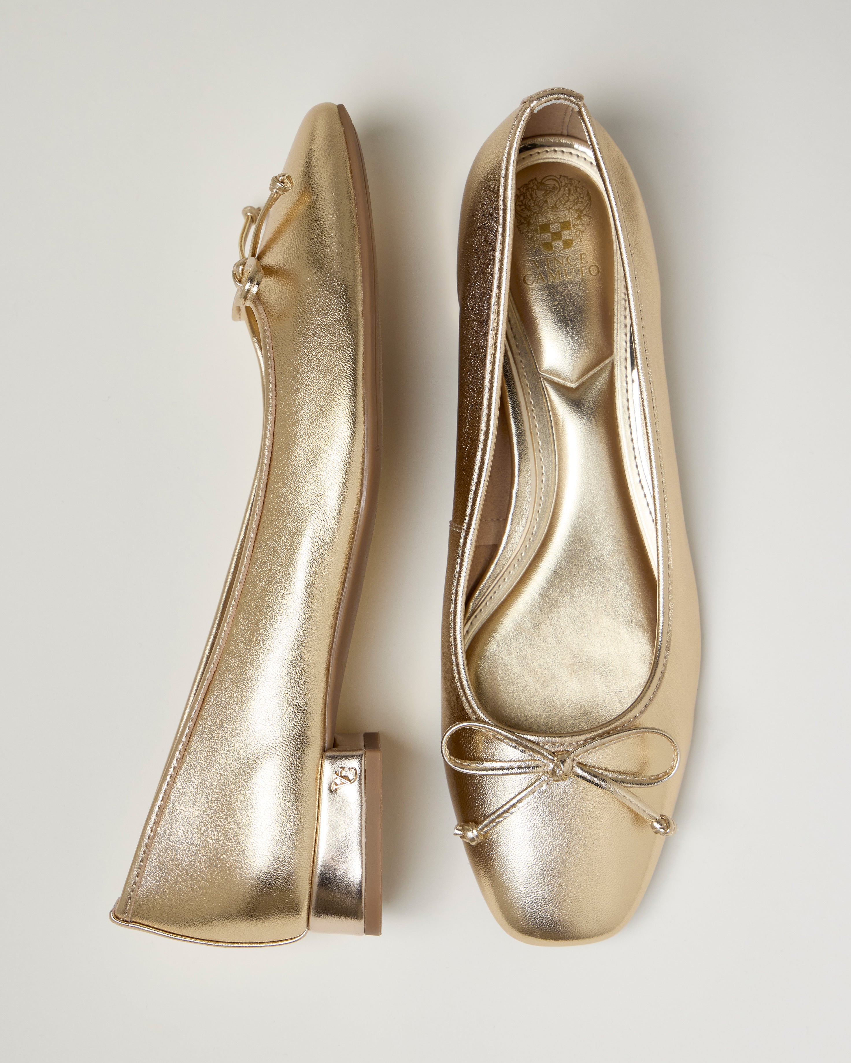 The Vince Camuto Jenlea Ballet Flat features metallic gold color, small bows on the square toes, and low block heels, shown from side and top views on a light background.