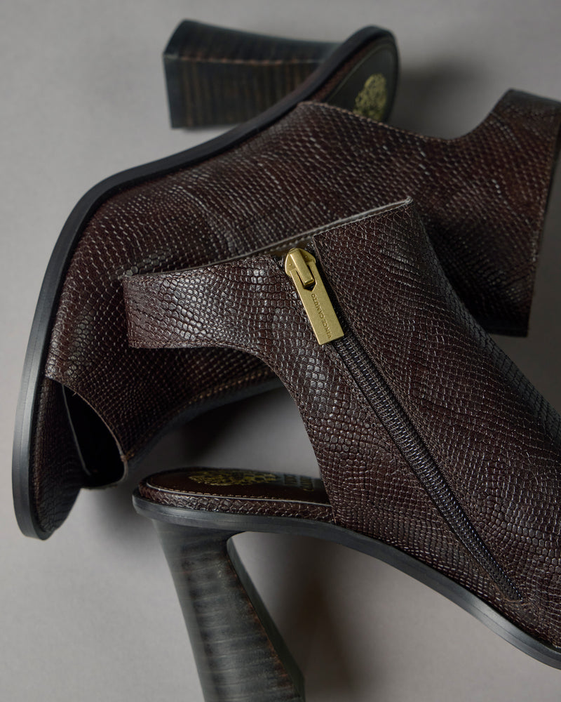 A close-up of two Rimdia Sandals by Vince Camuto, featuring brown textured leather, side zippers, and chunky block heels, arranged on a grey surface.
