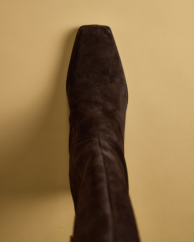 A top view of the Vince Camuto Sangeti Narrow Calf Boot in dark brown suede features a square toe and subtle block heel, displayed against a beige background.
