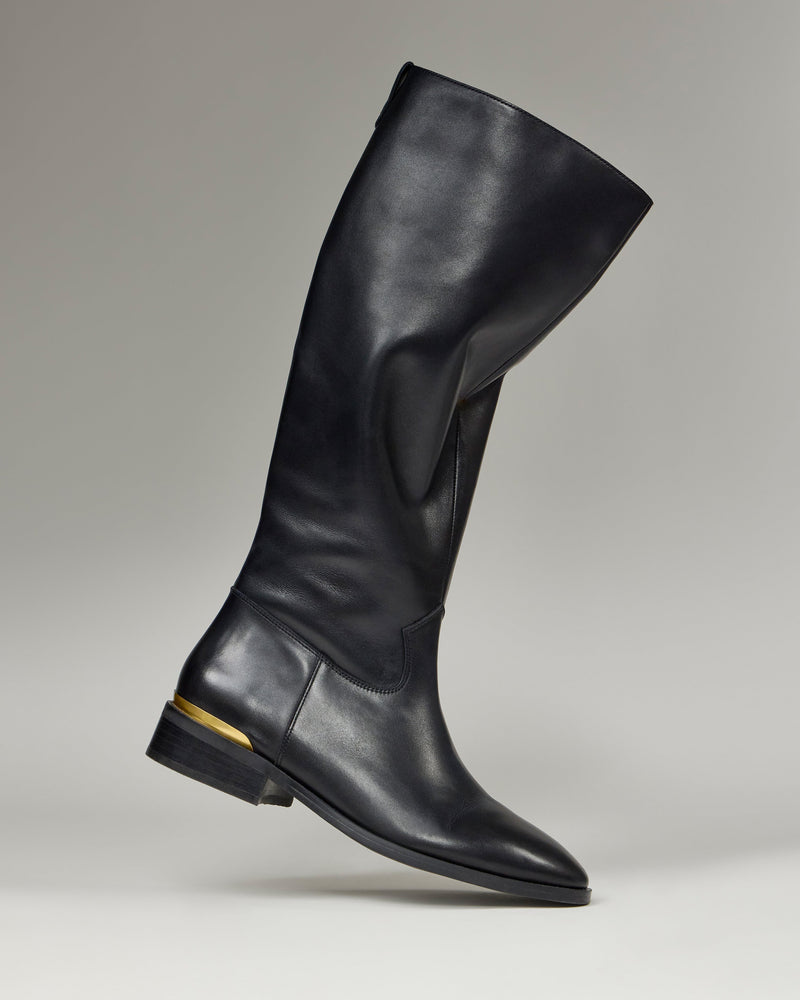 The Vince Camuto Bercla Narrow Calf Knee High Riding Boot features black leather, a low heel, and a gold accent near the back, shown against a plain gray background.
