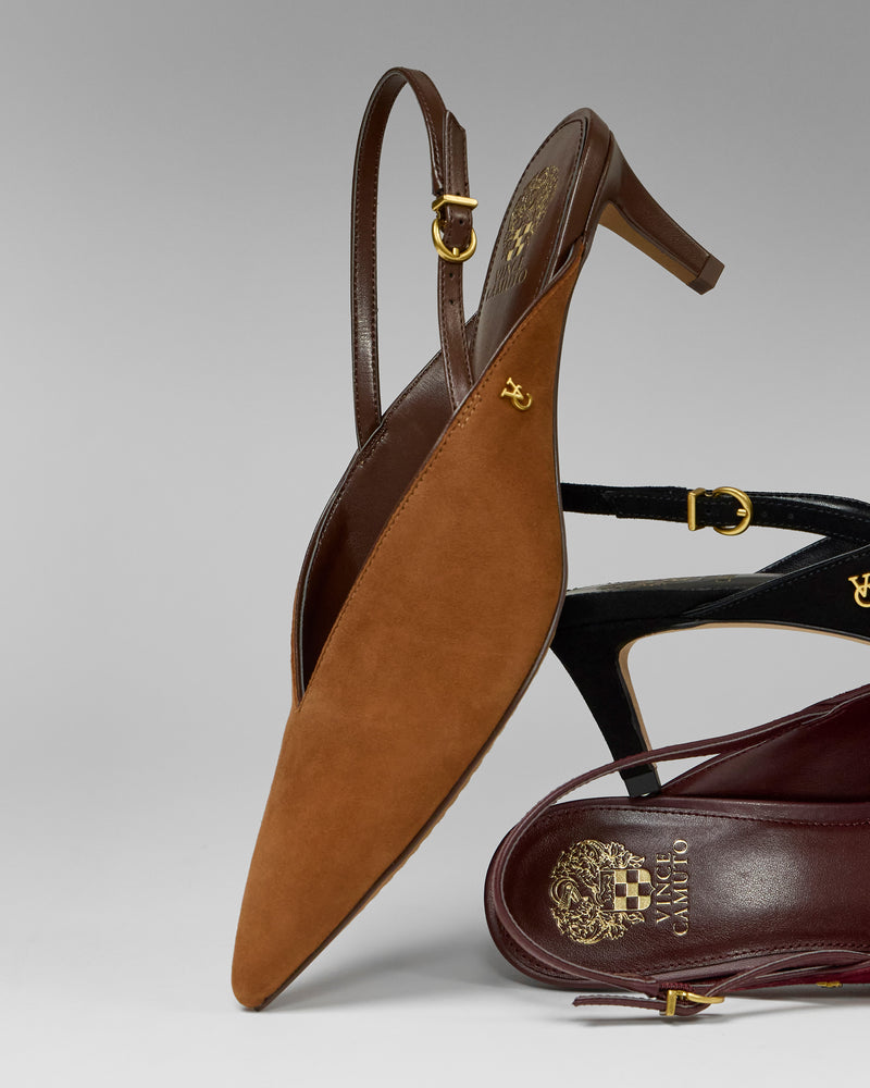 A close-up of three Vince Camuto Kylien Kitten Heel Pumps in brown, black, and burgundy suede with gold accents, featuring pointed toes and slingback design, stacked artistically against a plain gray background.