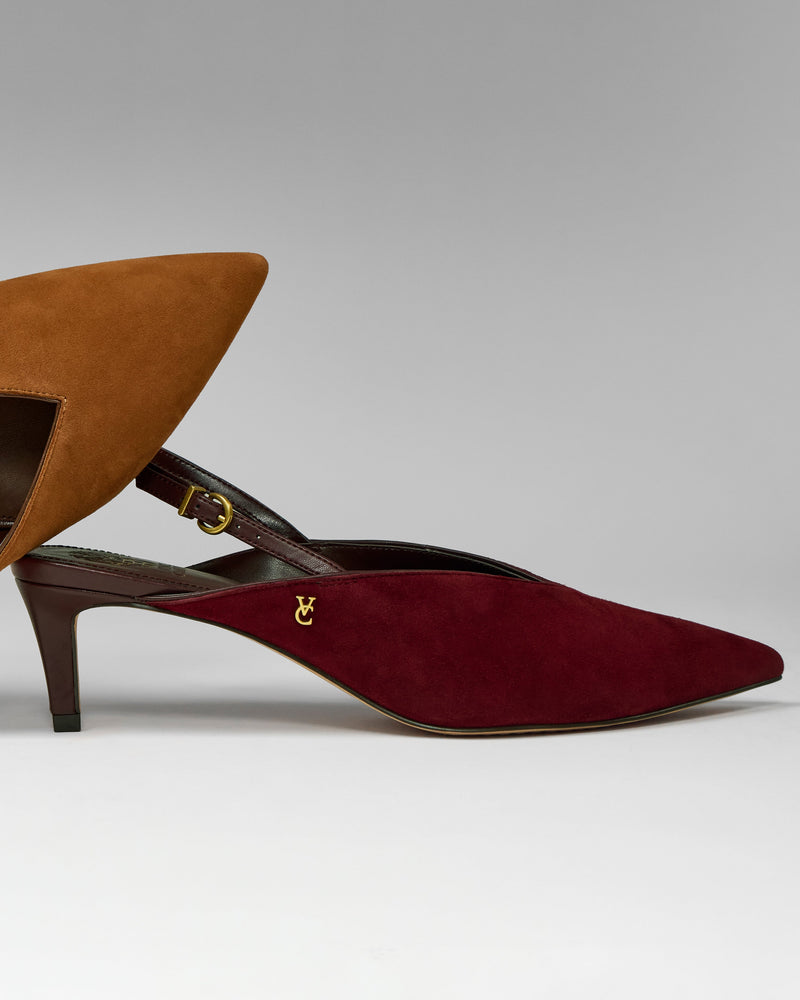 The Kylien Kitten Heel Pump by Vince Camuto in red suede, featuring a pointed toe and slingback design with a minimalist aesthetic, stands in front of a partially visible brown suede version—both showcasing thin kitten heels—set against a gray background.