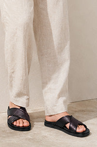 Person wearing black sandals with a plain background