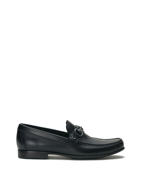 The Vince Camuto Men’s Caelan Loafer is a black leather slip-on with a low heel and buckle detail, displayed in side profile against a white background—these classic loafers are an ideal choice for stylish office footwear.