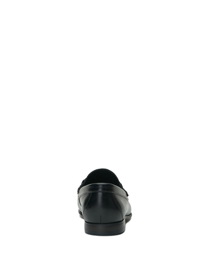 The Vince Camuto Men’s Caelan Loafer, a single black leather shoe featuring classic horse-bit hardware, is shown from the back and centered on a plain white background.