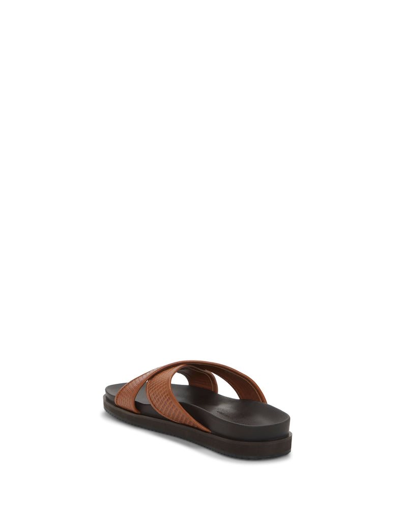 The Vince Camuto Men's Dabor Cross-Band Sandal features two brown crisscross leather straps and a flat black sole in a classic silhouette, shown from the back against a white background.
