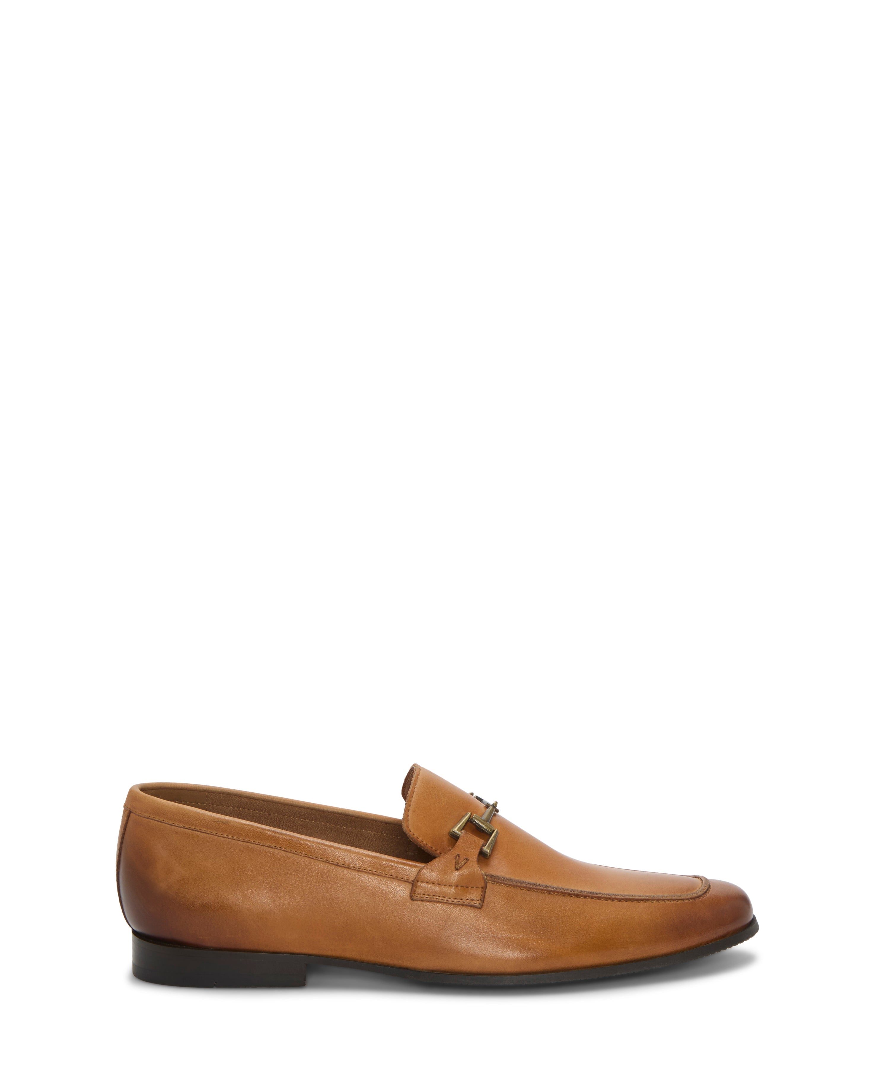 The Vince Camuto Men's Sevvano Dress Loafer is a tan leather slip-on with a low black heel, almond toe, and horse bit detail across the vamp, shown on a white background.