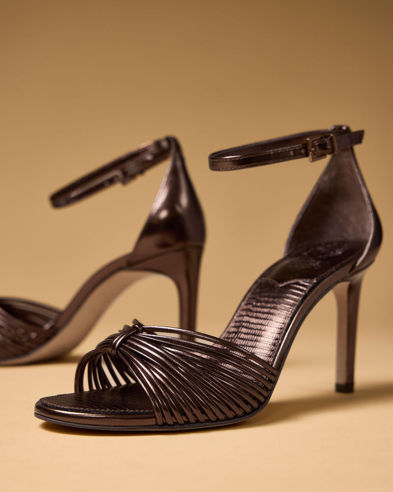 Vince Camuto Blaine metallic bronze strappy sandals with a tall heel, featuring multiple thin straps across the toe and an ankle strap with a buckle.
