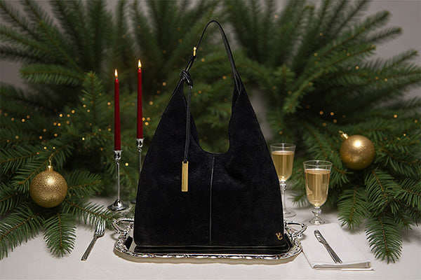 black handbag surrounded by elegant dinner wear 